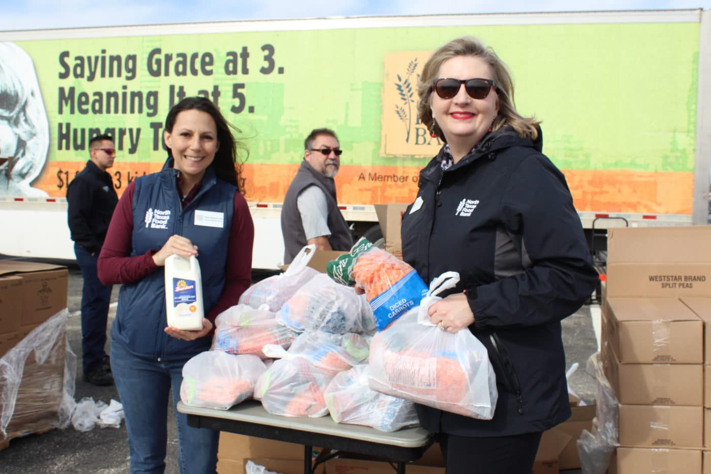 Valerie Hawthorne and Trisha Cunningham holding food at a North Texas Food Bank mobile pantry distribution