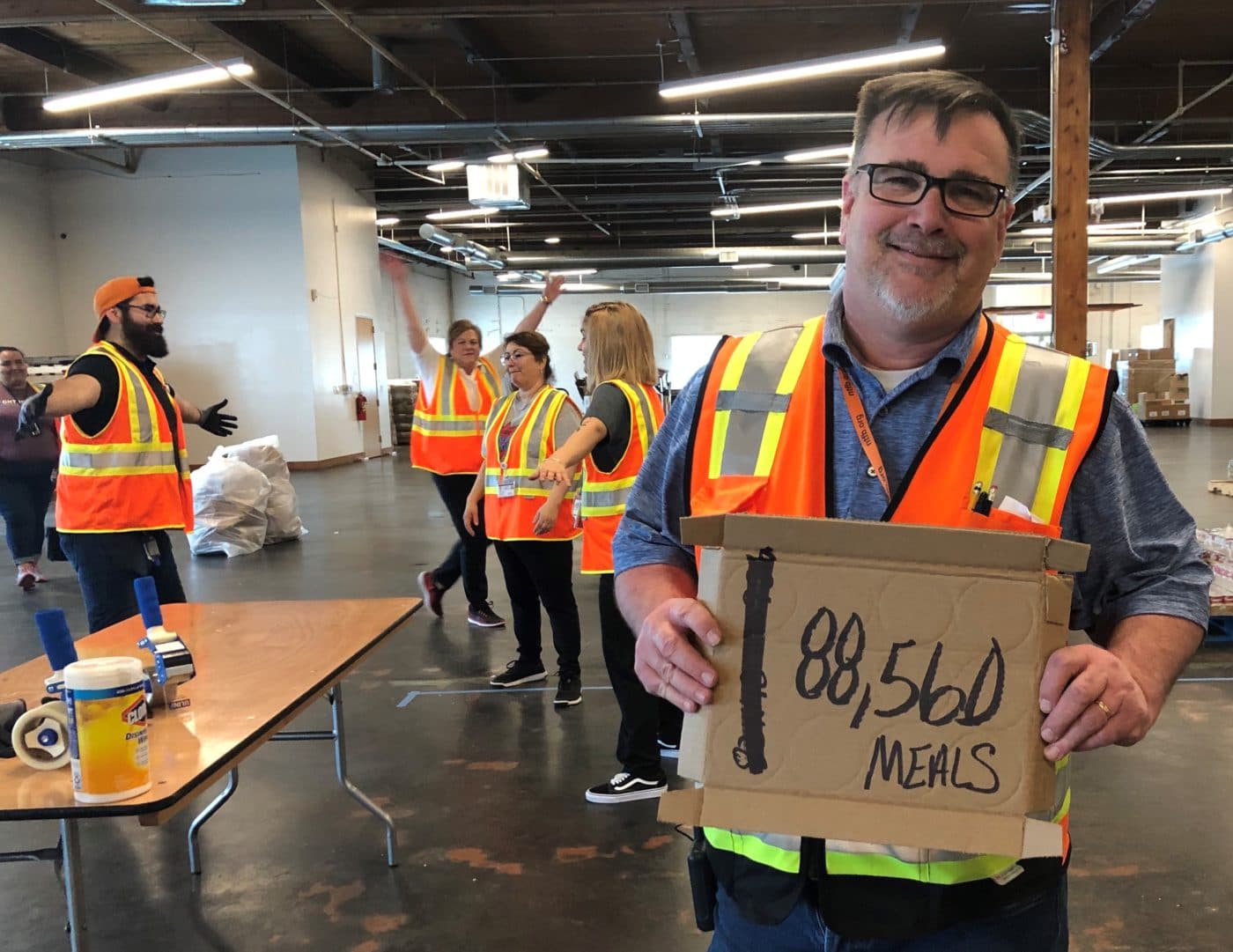 Man holding a piece of cardboard with 88,560 meals written on it