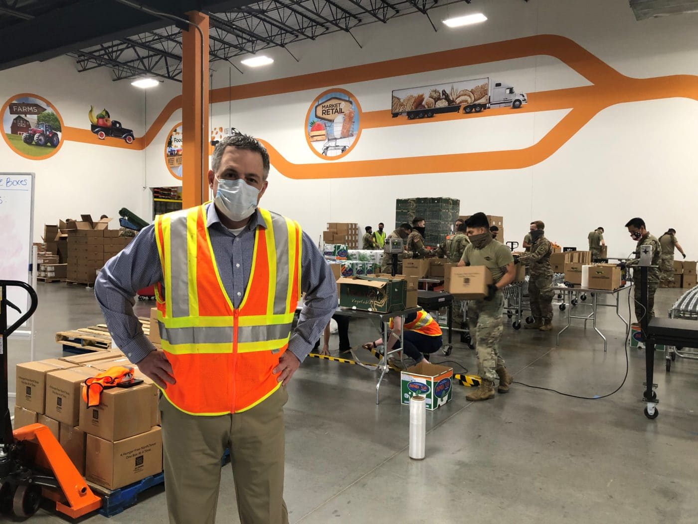 Brad Stewart in an orange safety vest on the volunteer floor of teh North Texas Food Bank