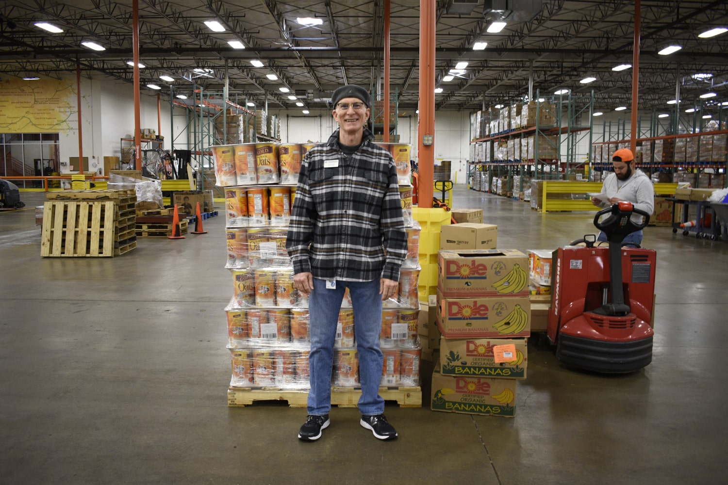Man smiling in front of boxes of Food at the North Texas Food Bank