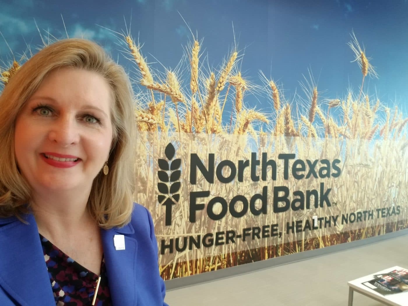Trisha Cunningham smiling in front of the North Texas Food Bank logo