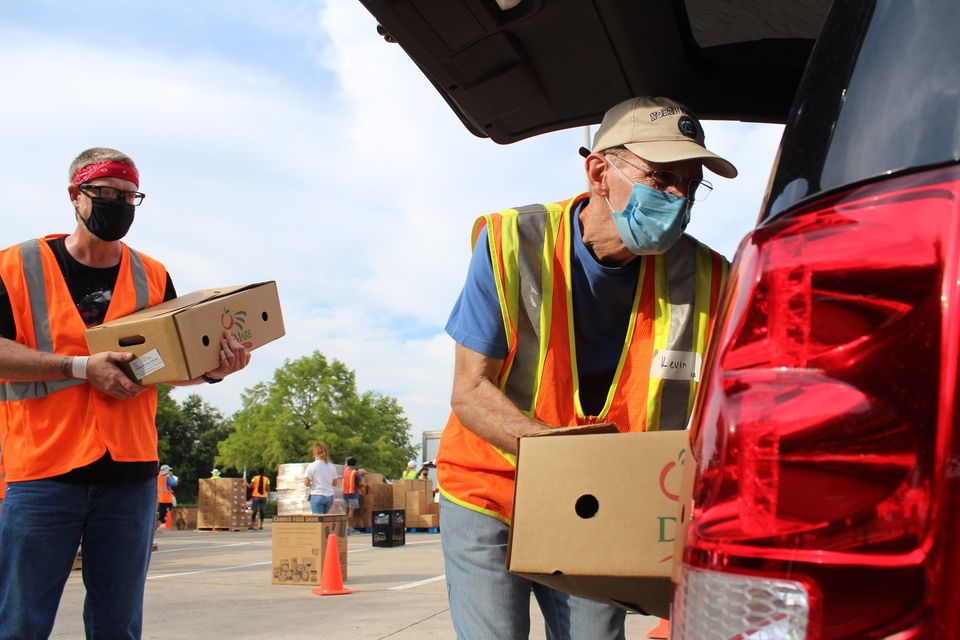North Texas Food Bank volunteer loading a box of food into the trunk of a car