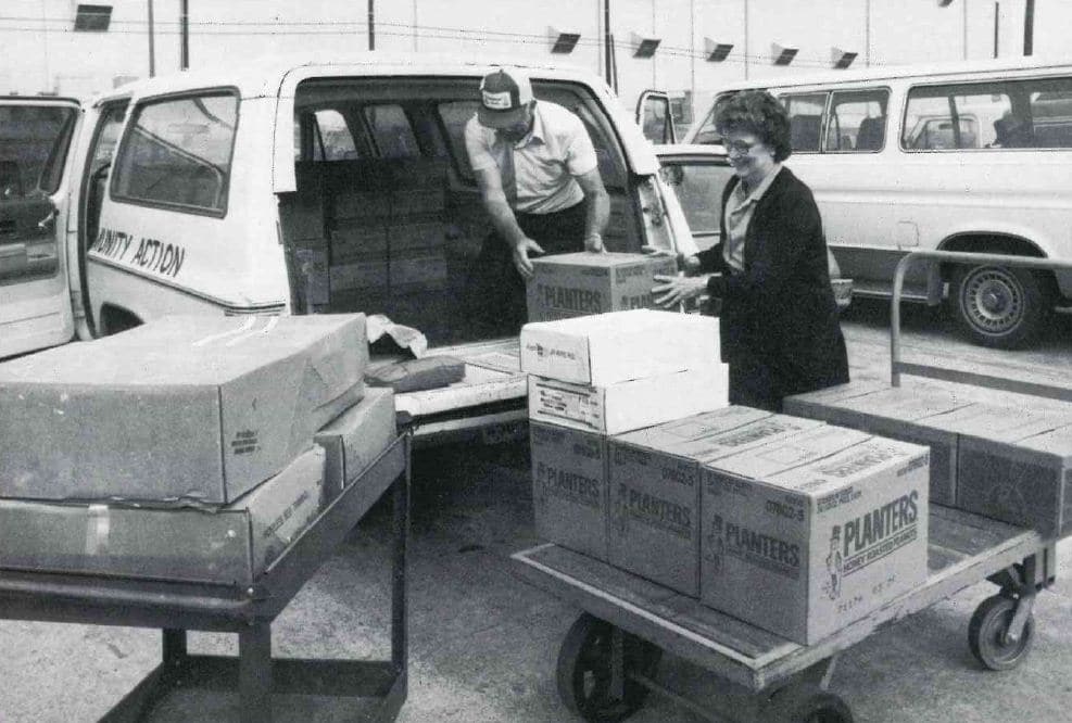 Black and white photo of NTFB volunteers loading boxes into a car