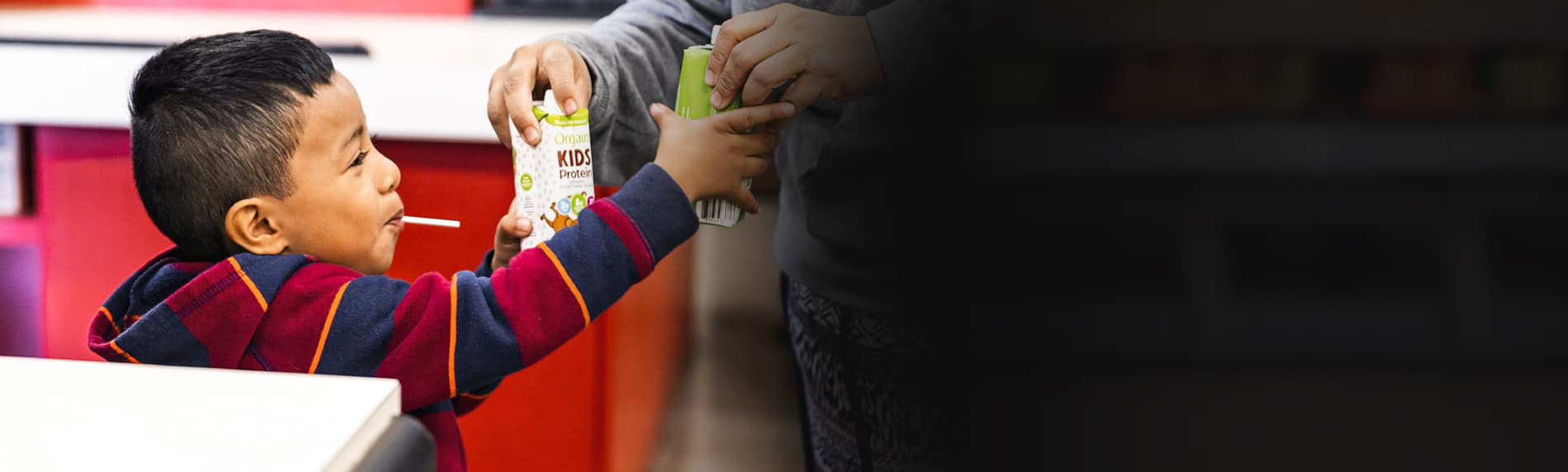 Young boy being handed juice boxes