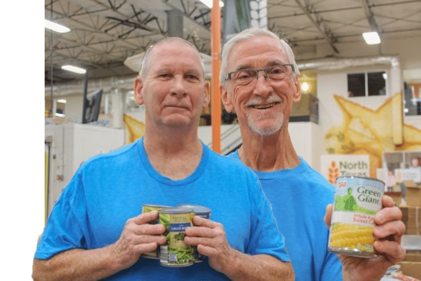 Two older white men in blue shirts holding canned goods
