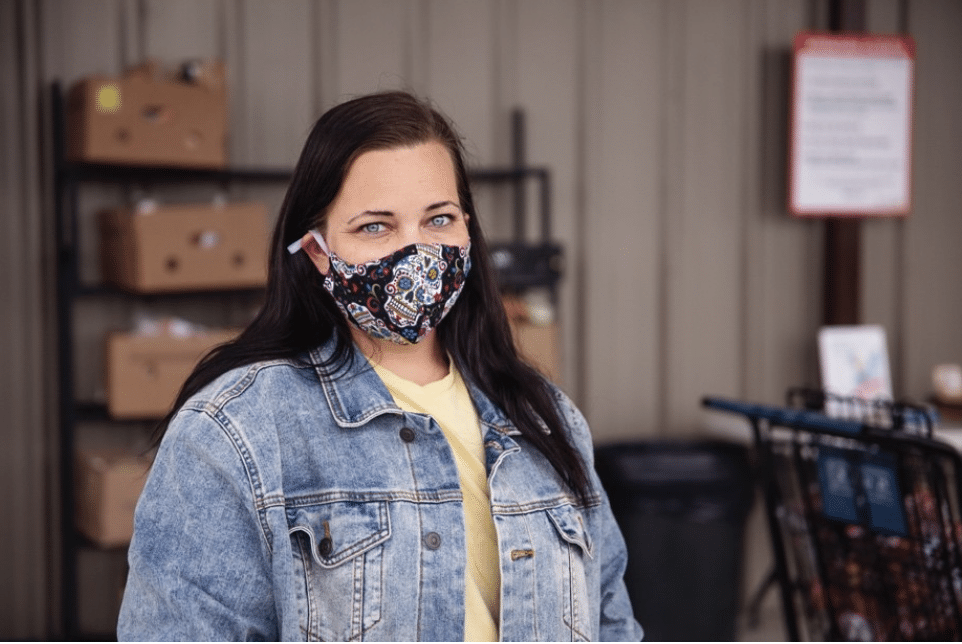 Young white woman with brown hair wearing a denim jacket and mask