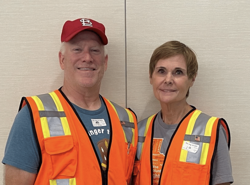 Older white couple wearing orange safety vests
