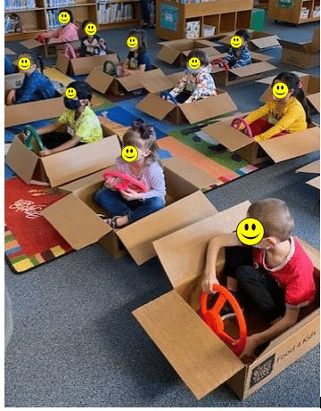 Kids in cardboard boxes as pretend cars.
