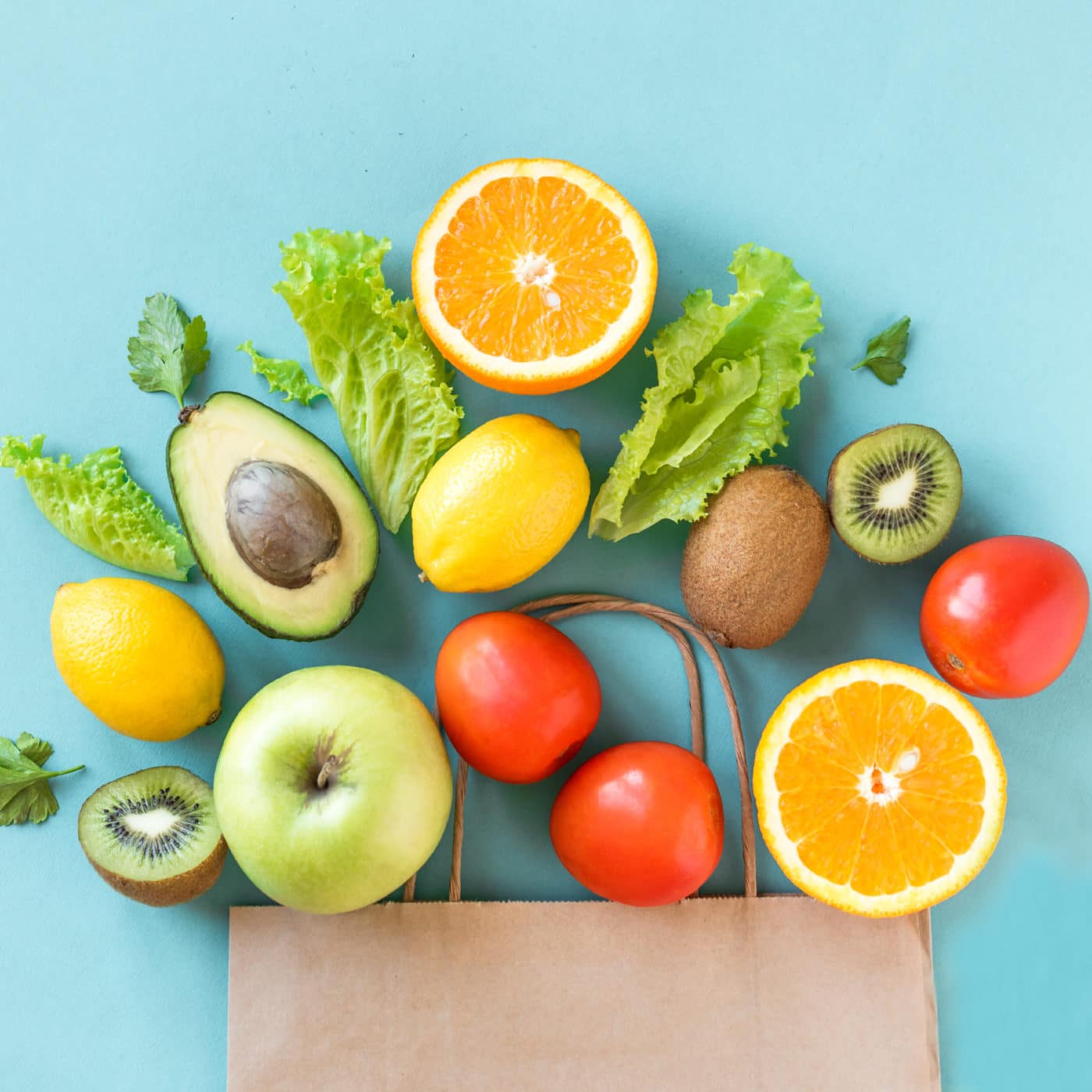Healthy food background. Healthy food in paper bag vegetables and fruits on blue, copy space. Shopping food supermarket concept.