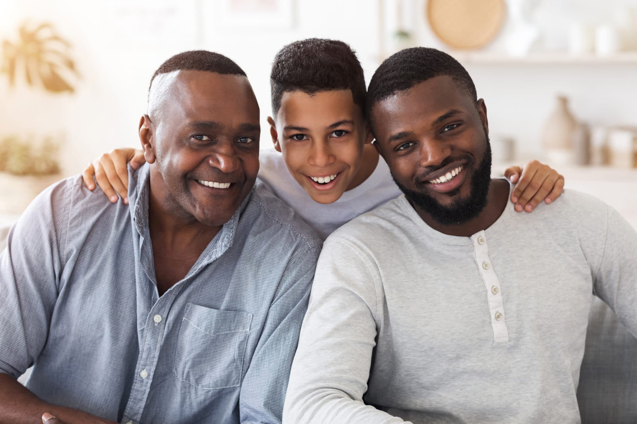 Portrait of joyful black son, dad and grandfather posing for family picture at home together