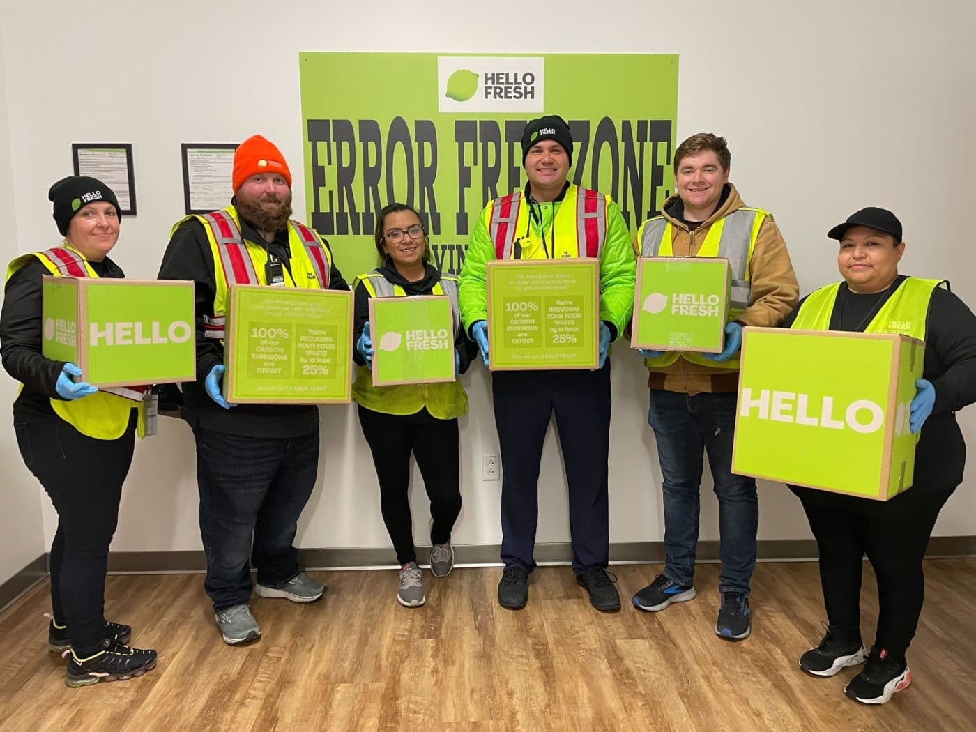 Six men and women standing holding HelloFresh food boxes