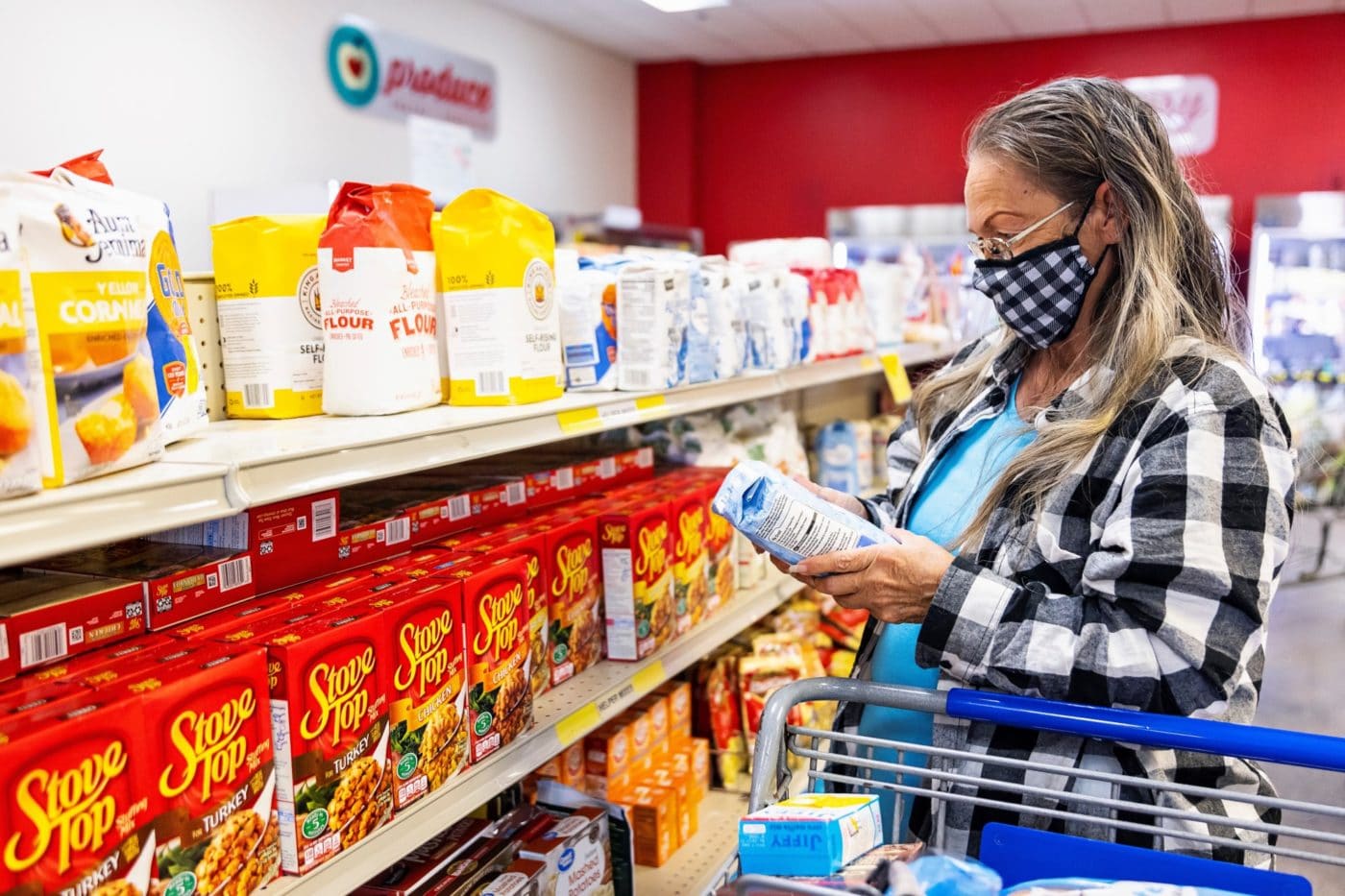 Woman in mask grocery shopping holding flour