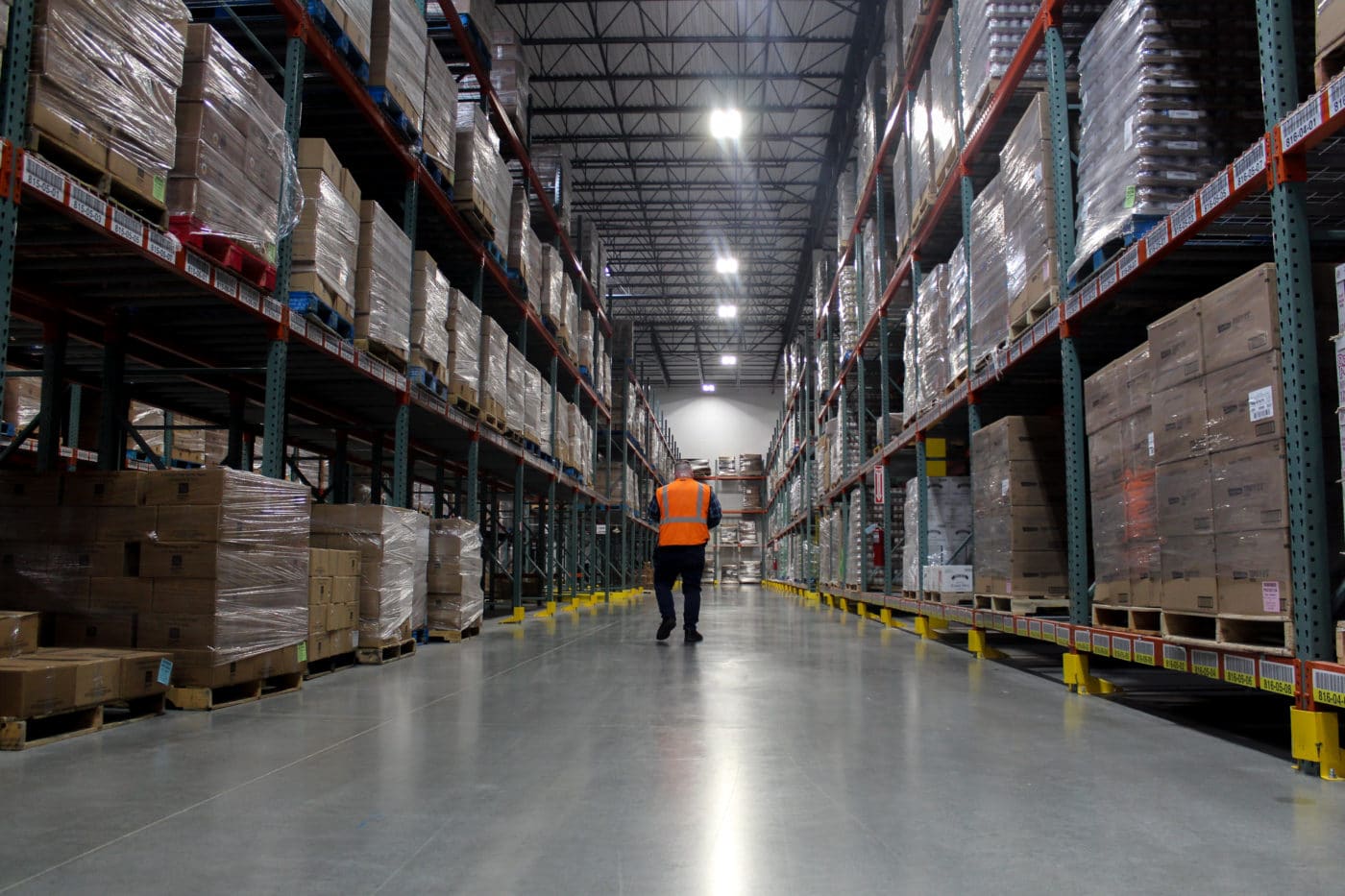 Warehouse aisle with boxes man in orange safety vest