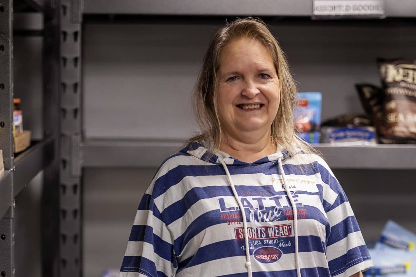 Older woman with blue and white striped shirt in front of pantry shelves