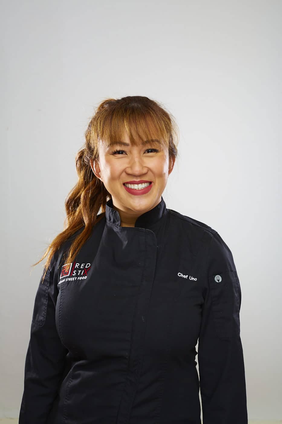 Woman with black chef top and brown hair and smiling