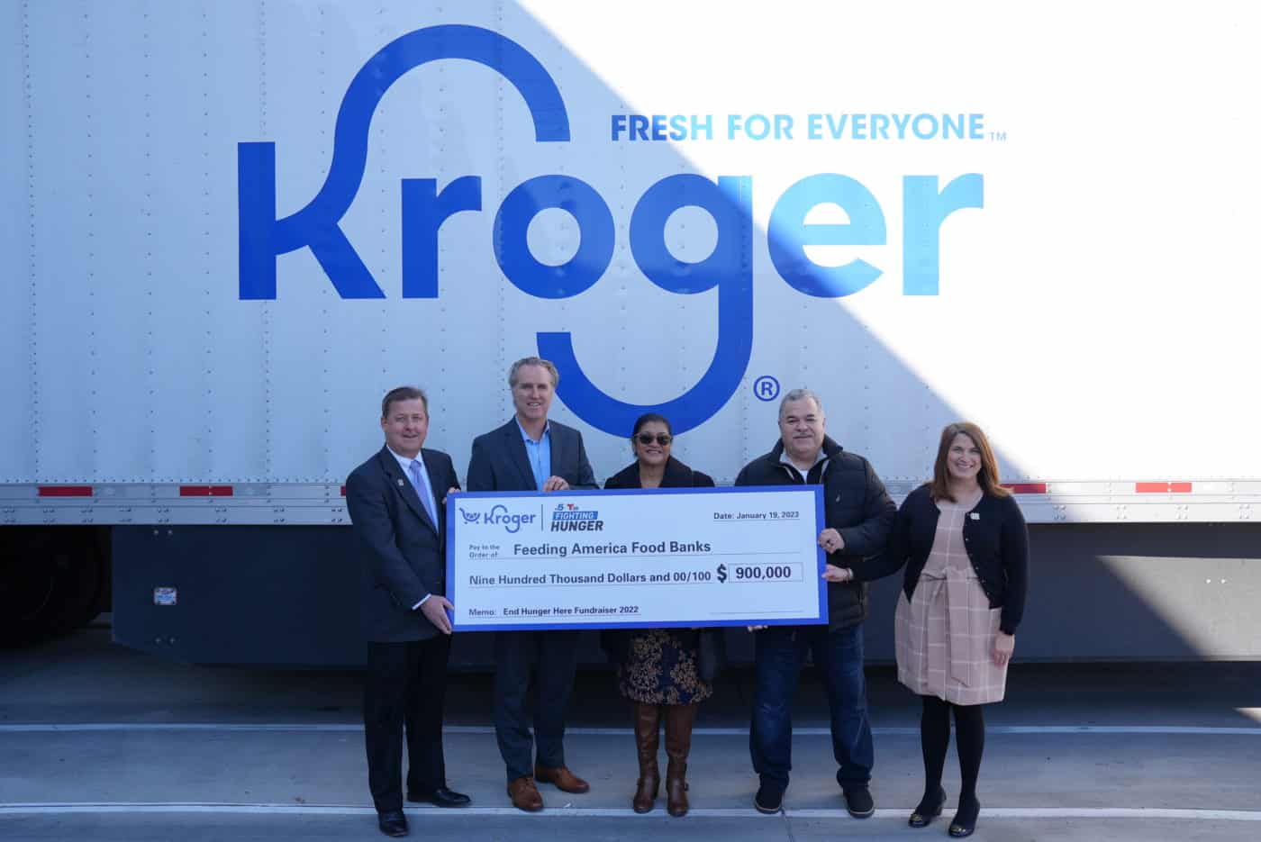 Five people holding a check in front of a Kroger truck
