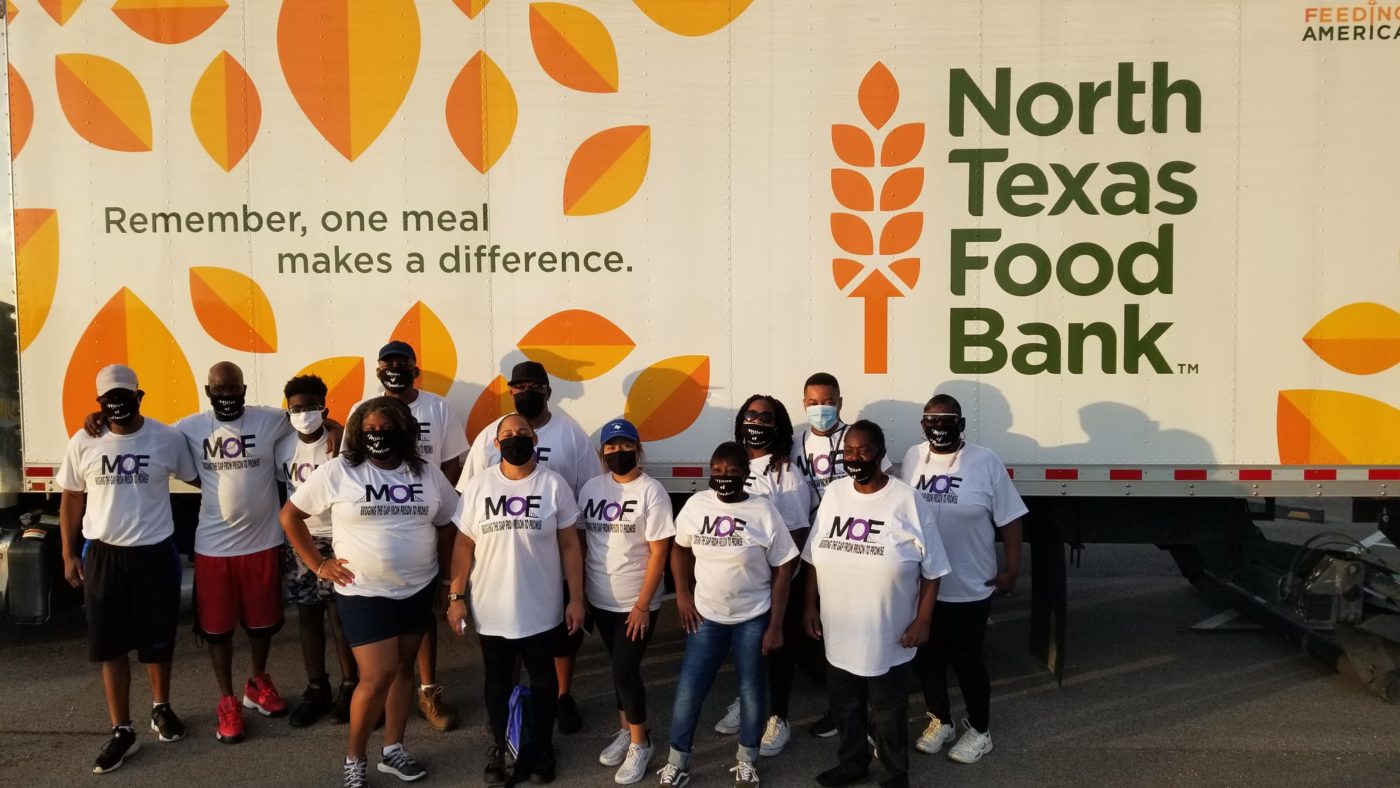 Group of people with masks on in front of North Texas Food Bank truck.