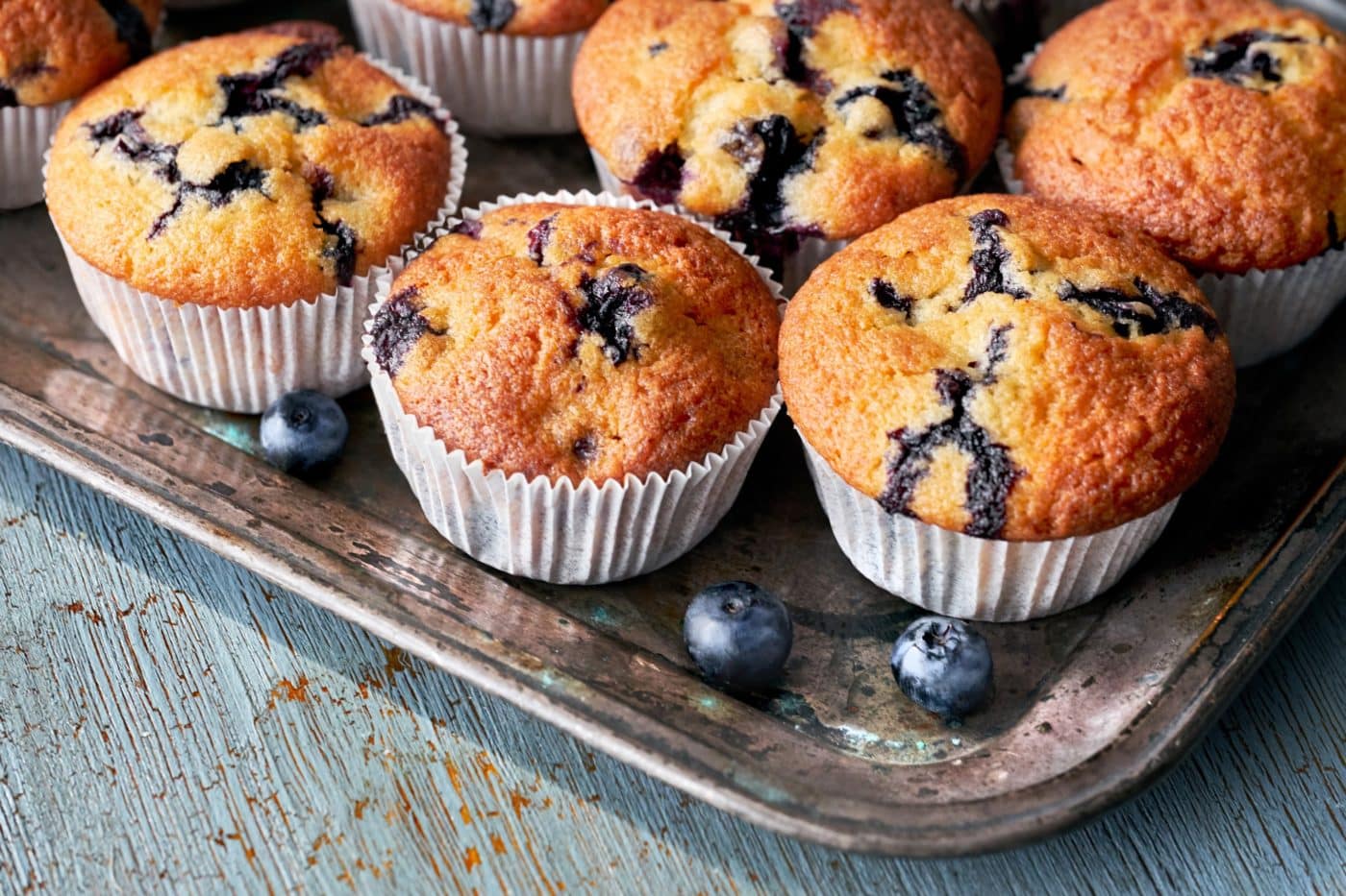 Tasty blueberry muffins on old baking tray sitting on rustic wooden table, text space