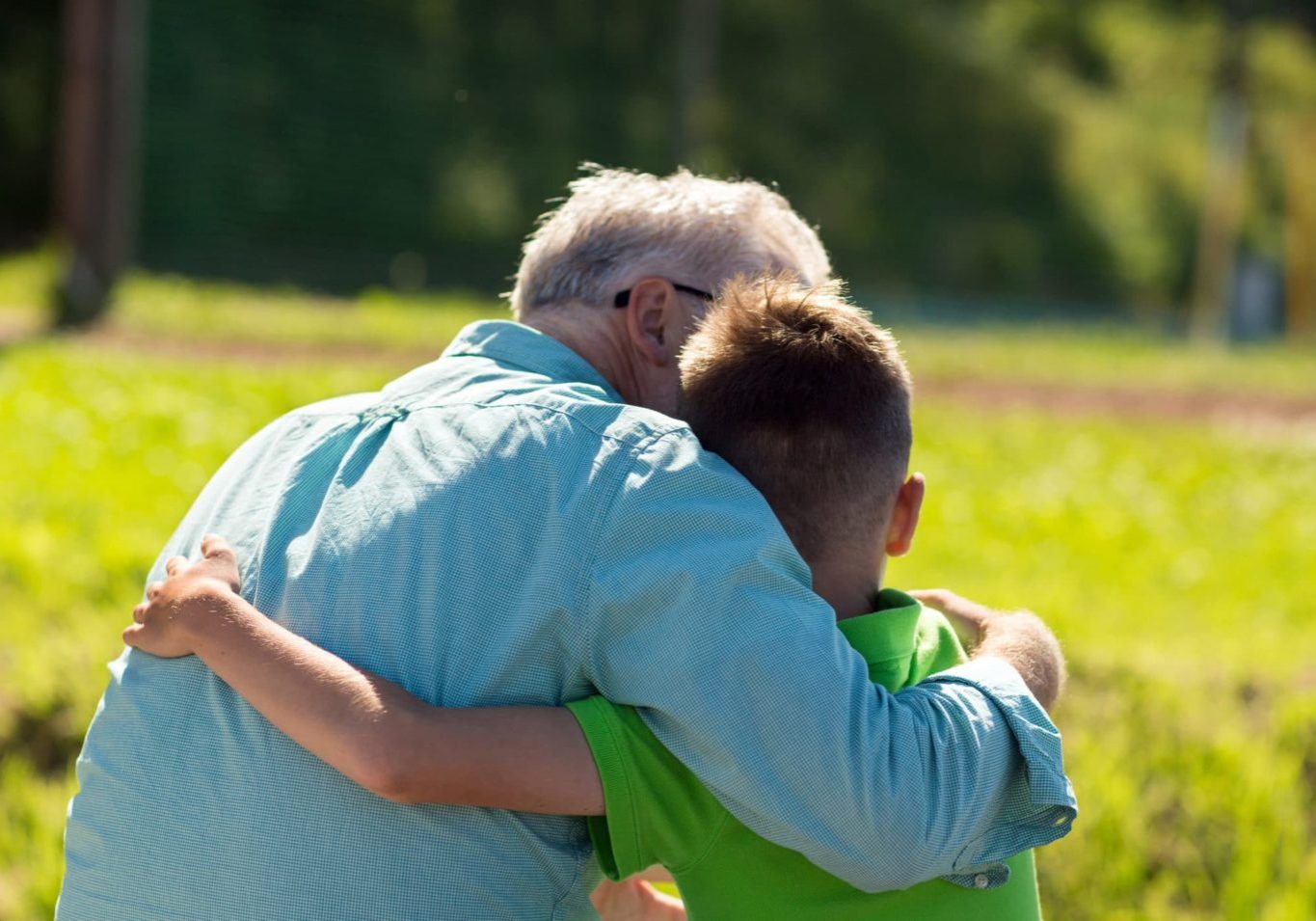 family, generation, relations and people concept - happy grandfather and grandson hugging outdoors