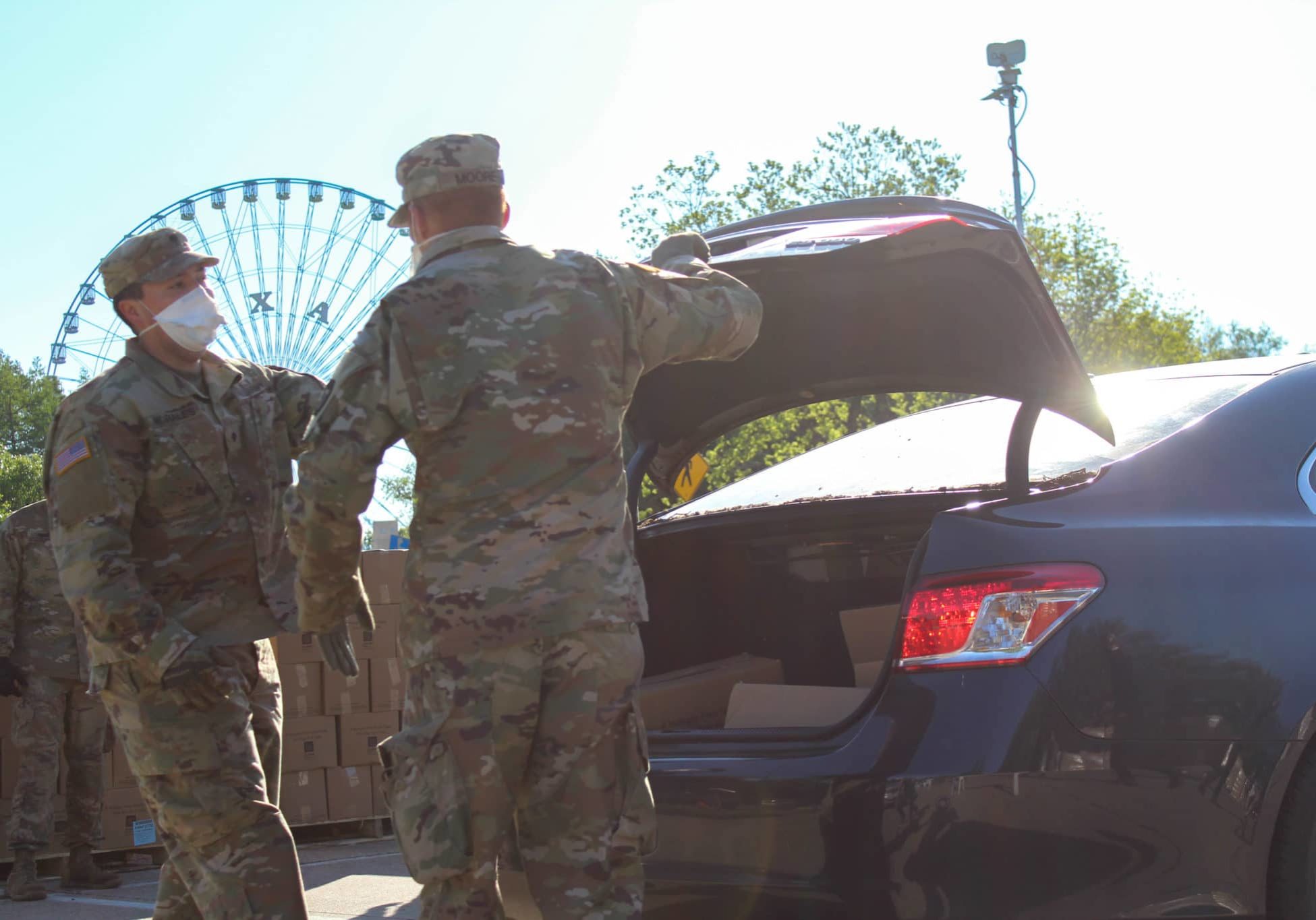 National Guard members putting boxes of food into car trunks at a Fair Park Mobile Pantry distribution led by the North Texas Food Bank