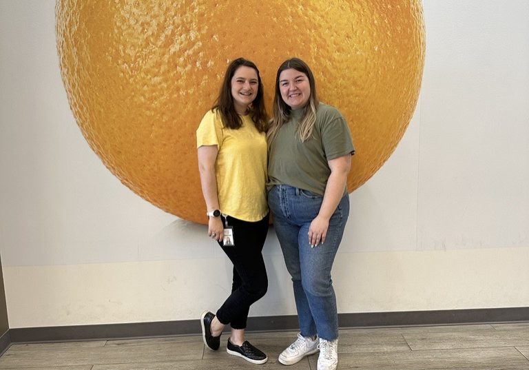 Two women posing in front of NTFB logo