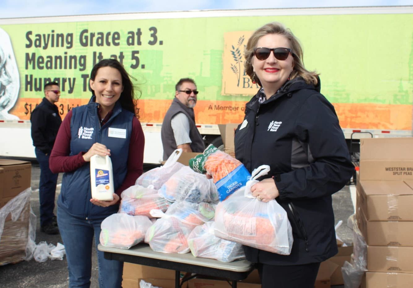 Valerie Hawthorne and Trisha Cunningham holding food at a North Texas Food Bank mobile pantry distribution