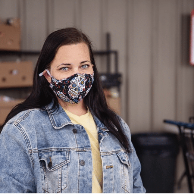 Young white woman with brown hair wearing a denim jacket and mask