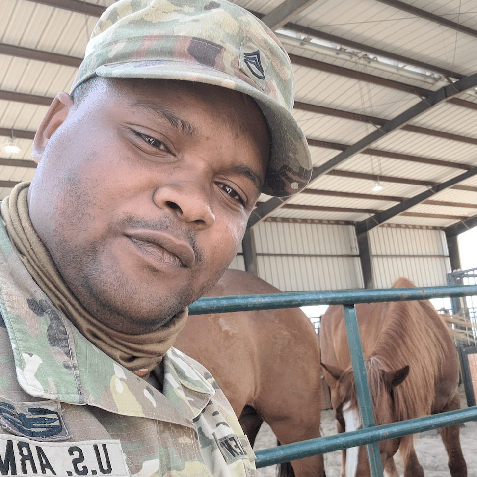 Seargent Allen in his US Army uniform in front of horses