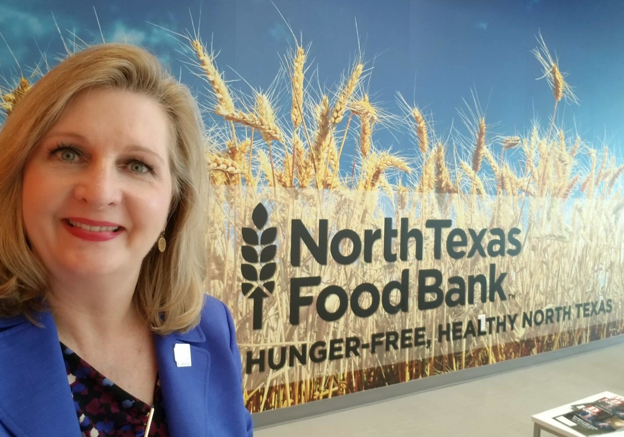 Trisha Cunningham smiling in front of the North Texas Food Bank logo
