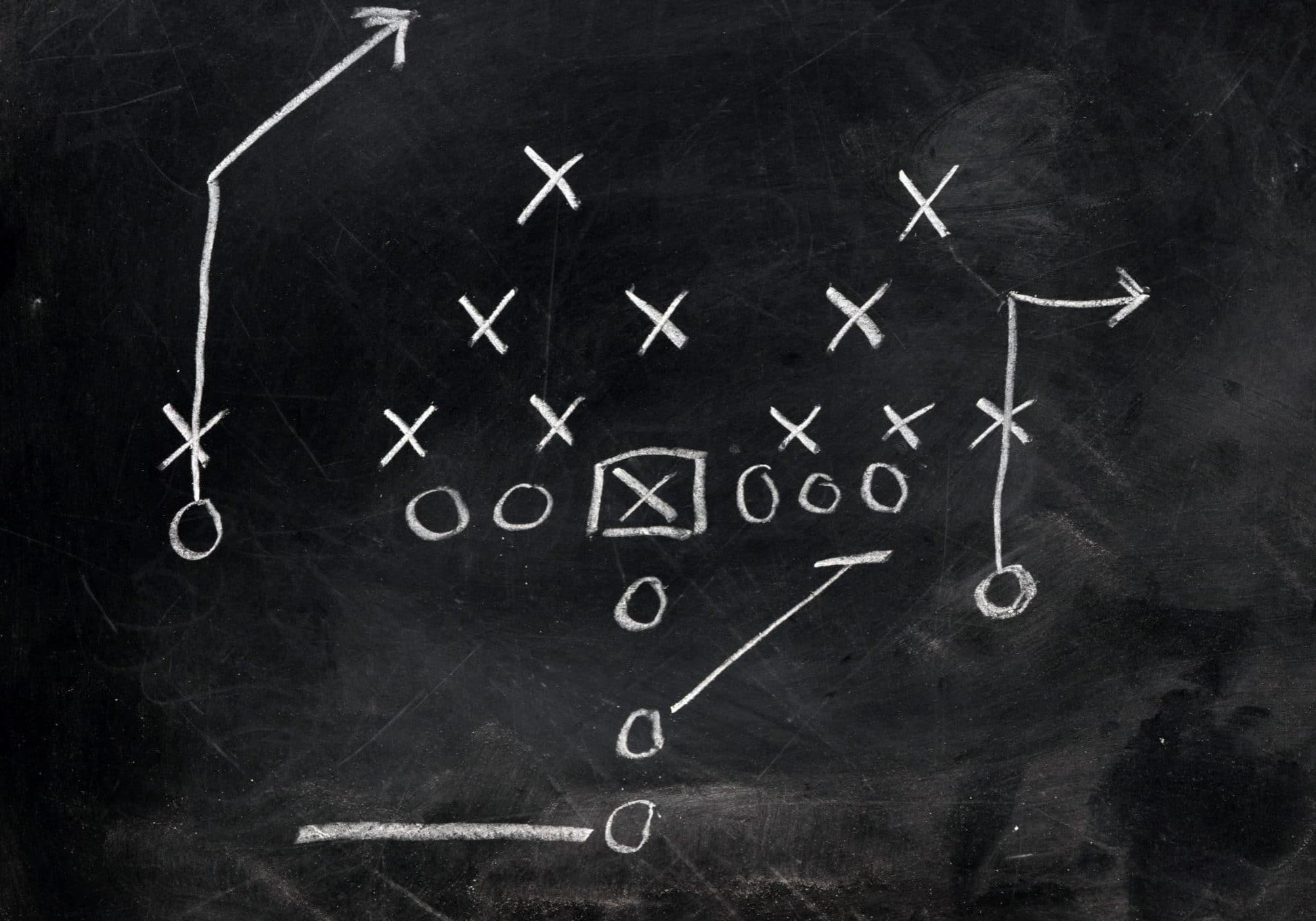 Diagram of football play on black chalkboard.